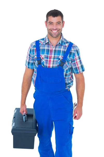 Happy handyman in coveralls carrying toolbox — Stock Photo, Image