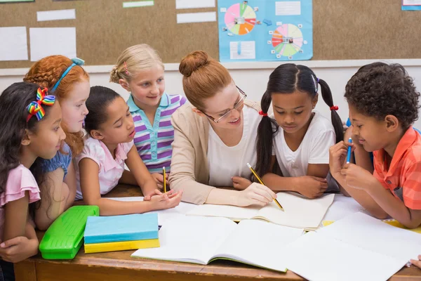 Teacher and pupils working at desk together — Stock Photo, Image