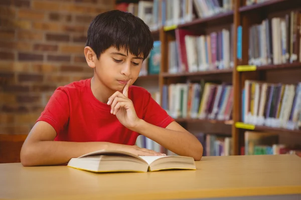 Ładny chłopiec czytanie książki w bibliotece — Zdjęcie stockowe