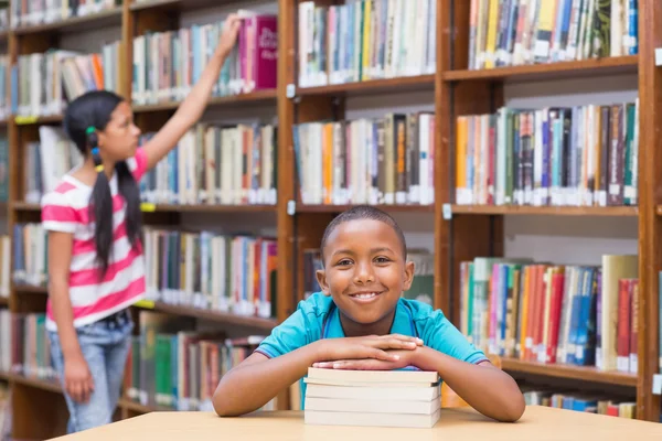 かわいい生徒の図書館にある本を探しています — ストック写真