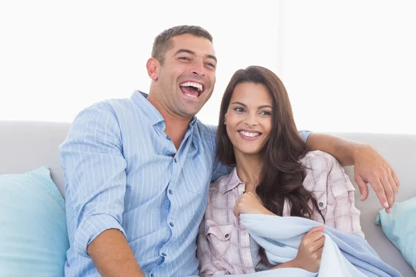 Glada par tittar på tv på soffan — Stockfoto