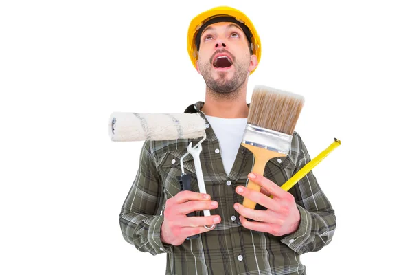 Screaming manual worker holding various tools — Stock Photo, Image