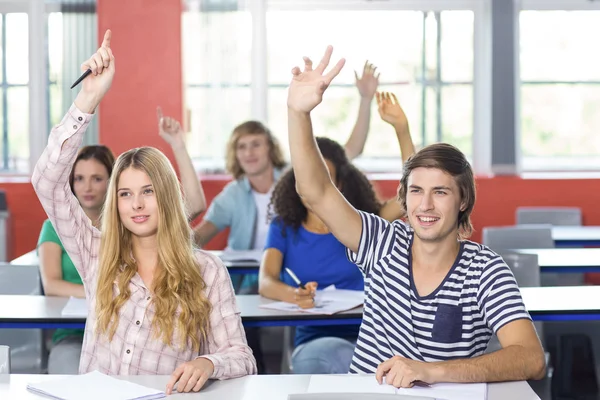 Estudantes levantando as mãos em sala de aula — Fotografia de Stock