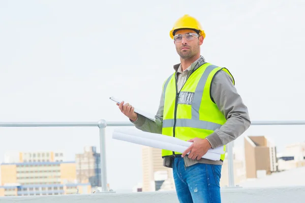 Architect holding blueprints and clipboard outdoors — Stock Photo, Image