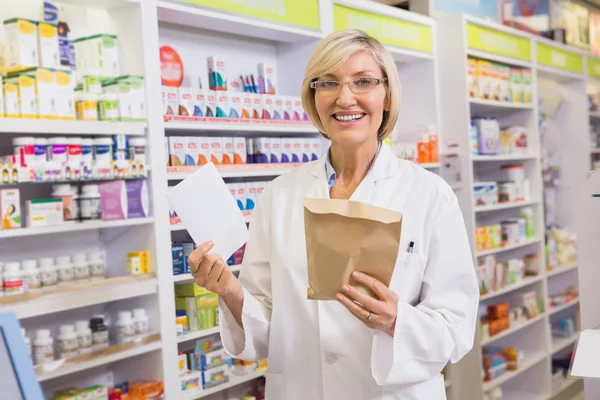 Farmacista sorridente in possesso di prescrizione e busta — Foto Stock