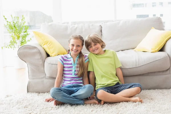 Happy siblings sitting on rug — Stock Photo, Image