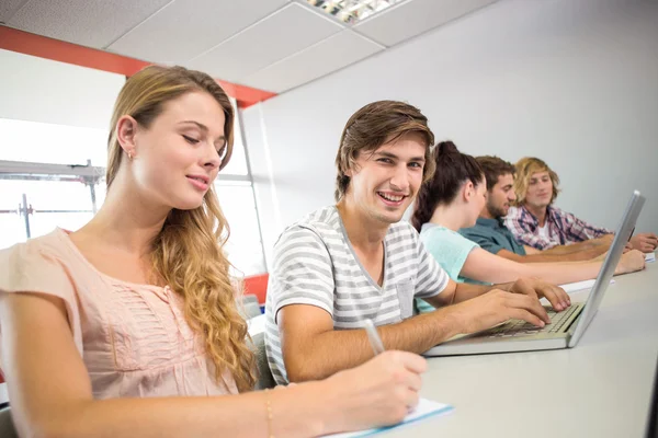 Students writing notes in classroom — Stock Photo, Image