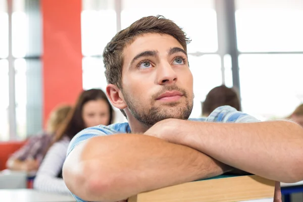 Eftertänksam student med böcker i klassrummet — Stockfoto