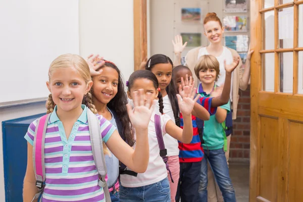Mignons élèves agitant à la caméra dans la salle de classe — Photo