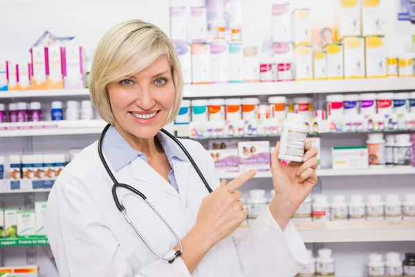Médico sonriente señalando un frasco de droga —  Fotos de Stock
