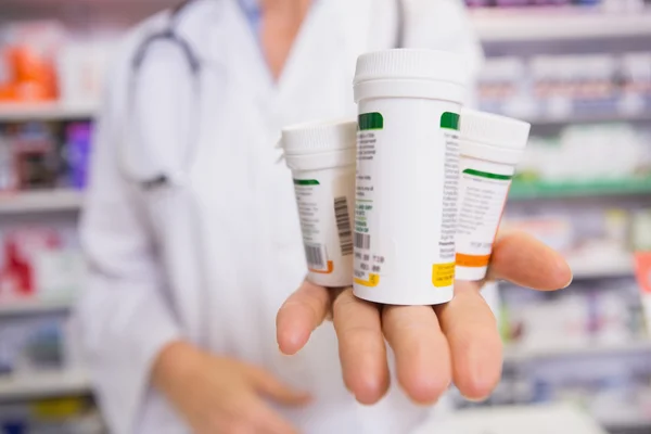 Farmacêutica apresentando medicamentos em sua mão — Fotografia de Stock
