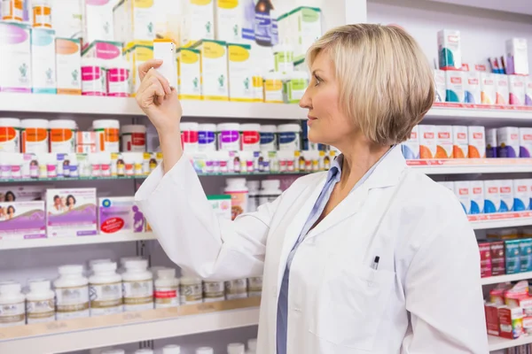 Smiling pharmacist looking at medicine — Stock Photo, Image