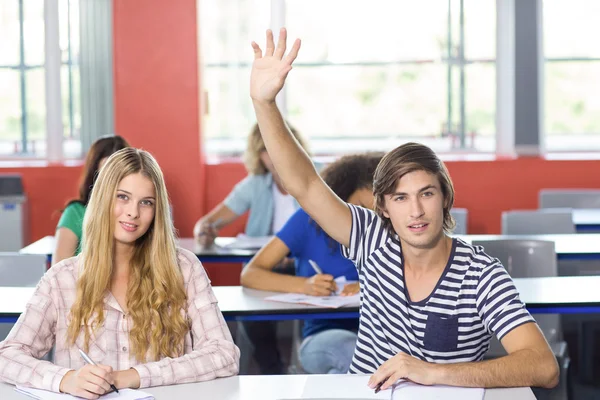 Estudante do sexo masculino levantando a mão em sala de aula — Fotografia de Stock