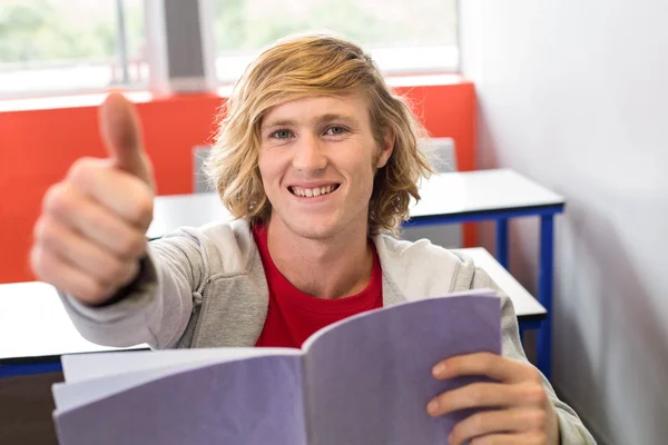 Hombre estudiante gesto pulgares hacia arriba en el aula — Foto de Stock
