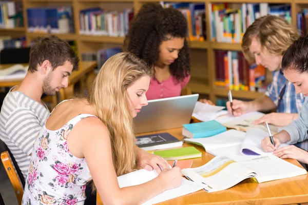 Estudantes universitários fazendo lição de casa na biblioteca — Fotografia de Stock