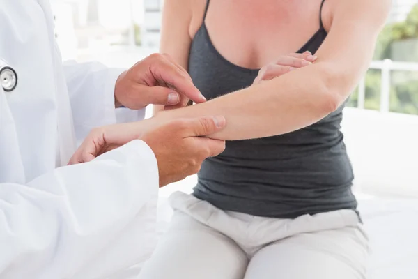 Médico examinando seu braço paciente — Fotografia de Stock