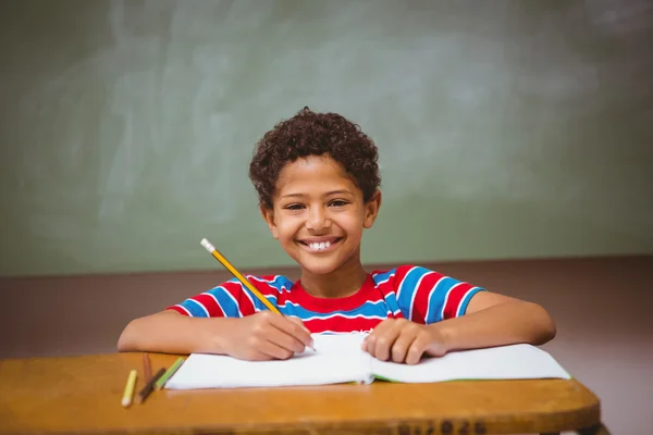 Kleine jongen schrijven boek in klas — Stockfoto