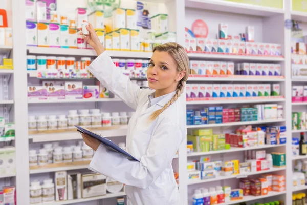 Farmacêutico júnior a tomar medicamentos na prateleira — Fotografia de Stock