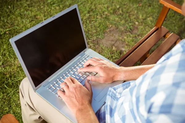 Człowiek siedzi na ławce w parku przy użyciu laptopa — Zdjęcie stockowe