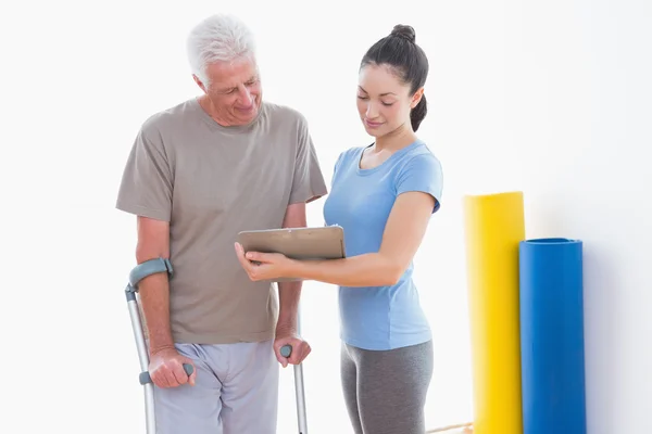 Senior man and his coach looking at clipboard — Stock Photo, Image