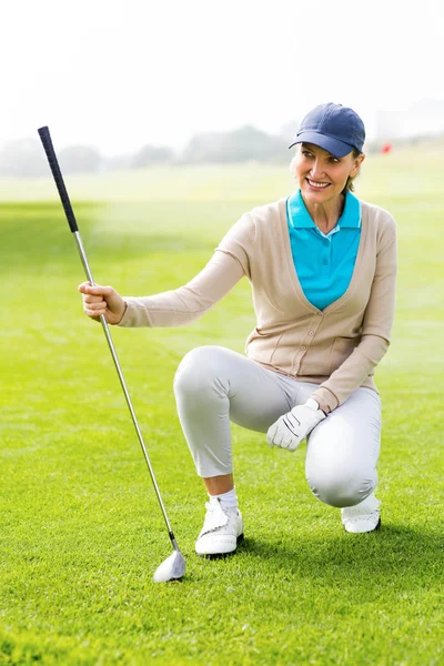 Feminino golfista kneeing no putting green — Fotografia de Stock