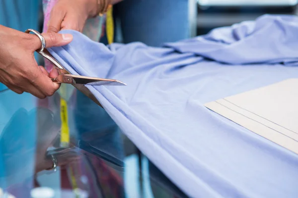 Manos cortando tela en la mesa — Foto de Stock