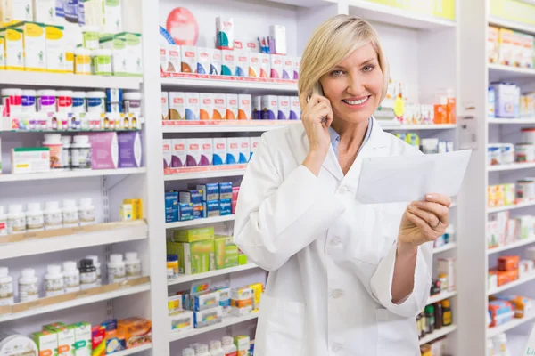 Farmacista sorridente al telefono lettura prescrizione — Foto Stock