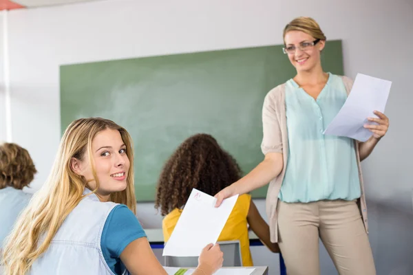 Professora entrega papel para aluno em sala de aula — Fotografia de Stock