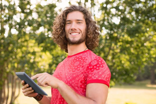 Handsome hipster using tablet pc in the park — Stock Photo, Image