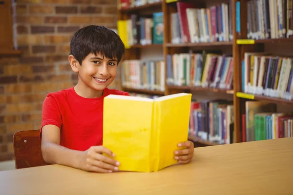 Retrato de menino lendo livro na biblioteca — Fotografia de Stock