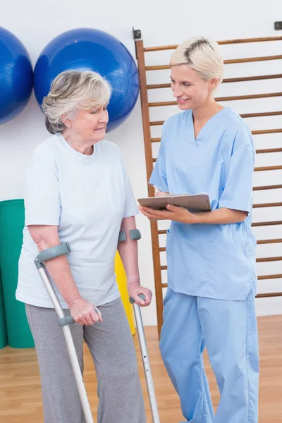 Therapist and senior woman looking at clipboard — Stock Photo, Image