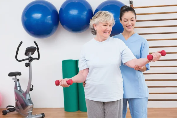 Therapeutin hilft Seniorin beim Einbau von Hanteln — Stockfoto