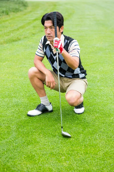 Crouching golfer holding club looking away — Stock Photo, Image