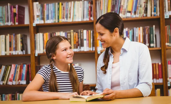 Professor e menina lendo livro na biblioteca — Fotografia de Stock