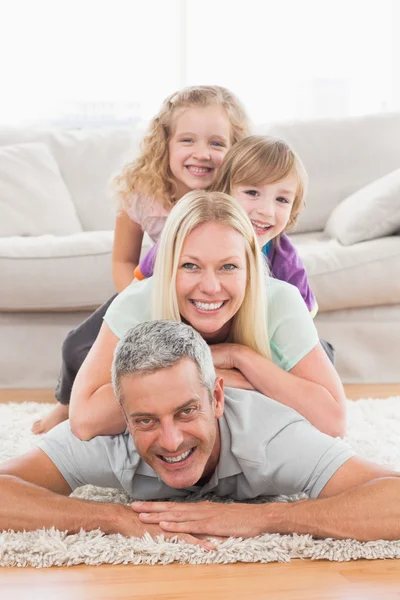 Speelse familie liggend op elkaar in woonkamer — Stockfoto