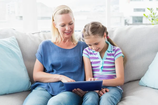 Madre con hija usando tableta digital en sofá —  Fotos de Stock