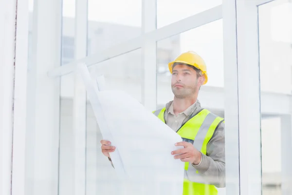 Arquitecto reflexivo sosteniendo el plano en la oficina —  Fotos de Stock