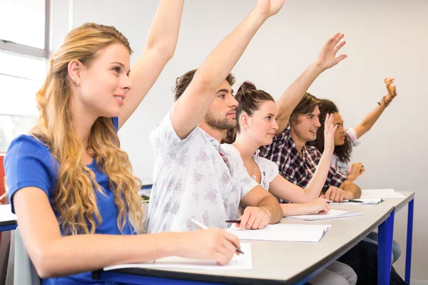 Students raising hands in classroom — Stock Photo, Image