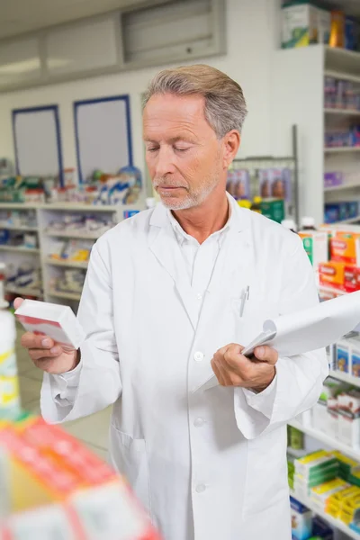 Senior pharmacist holding medicine and clipboard — Stock Photo, Image