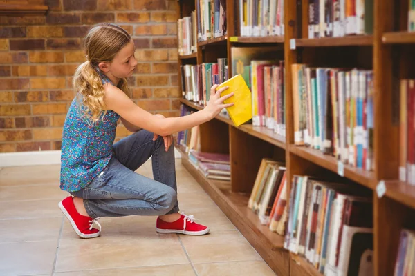 Schattig klein meisje boek in de bibliotheek te selecteren — Stockfoto