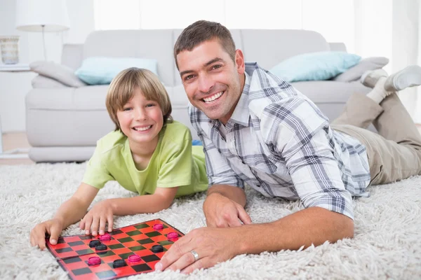 Father and son playing checker game on fur — Stock Photo, Image