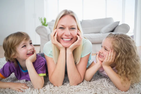 Kinderen kijken naar moeder liggen op tapijt — Stockfoto