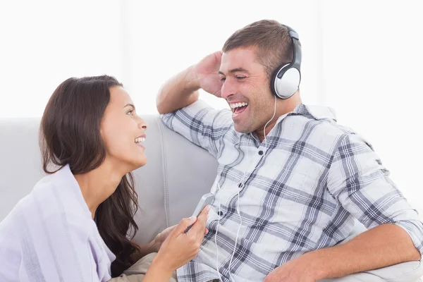 Mujer sosteniendo el teléfono móvil mientras el hombre escucha música — Foto de Stock