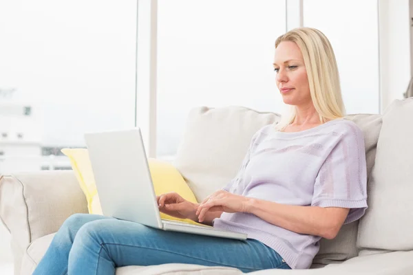 Frau benutzt Laptop auf Sofa — Stockfoto