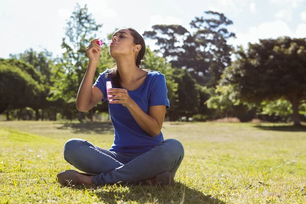 Mujer bonita soplando burbujas en el parque — Foto de Stock