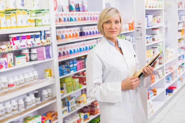 Serious pharmacist holding clipboard — Stock Photo, Image