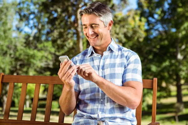 Man sitting on park bench with phone — Stock Photo, Image