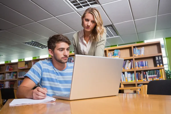 Estudante recebendo ajuda de tutor na biblioteca — Fotografia de Stock