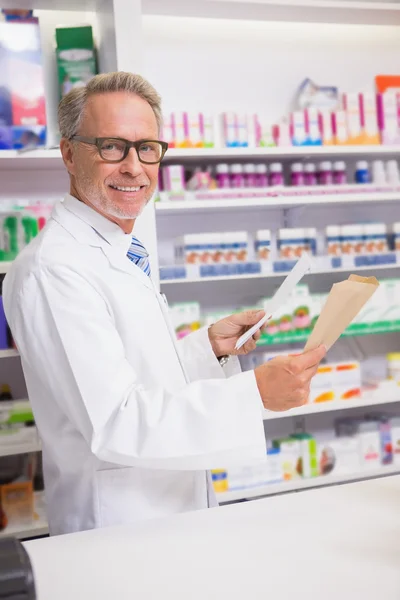 Smiling senior pharmacist holding prescription — Stock Photo, Image