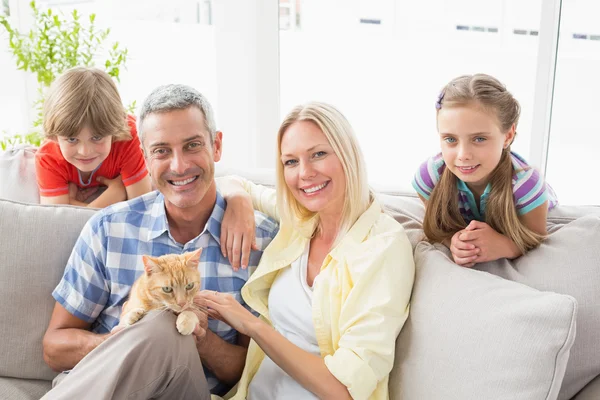 Familjen sitter med katt på soffa — Stockfoto